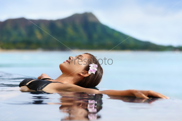 Hawaii vacation wellness pool spa woman relaxing in warm water at luxury hotel resort. Young adult at Waikiki beach in Honolulu, Oahu, Hawaii, USA.