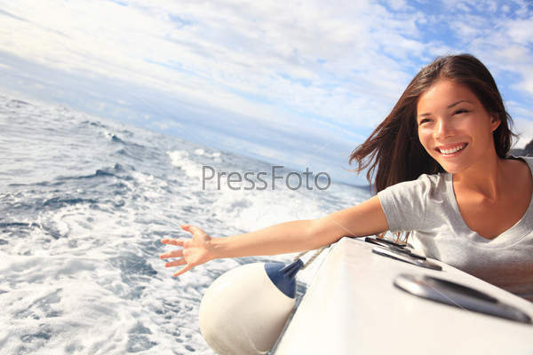 Boat woman smiling happy looking at the sea sailing by. Asian / Caucasian female model.