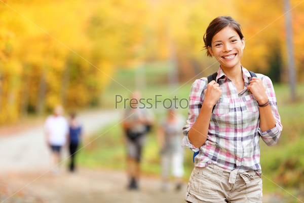 Autumn hiking girl. Female hiker looking around in forest in\
autumn colors. Beautiful young woman on hike.