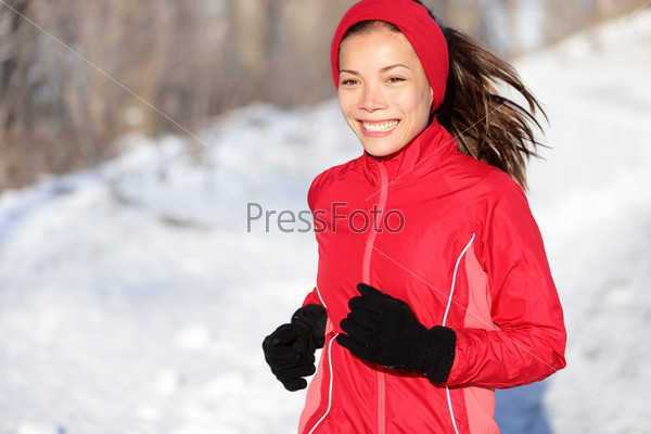 Fitness running woman in winter. Runner closeup of happy active sport model jogging in snow in winter forest. Beautiful mixed race asian chinese caucasian female model.