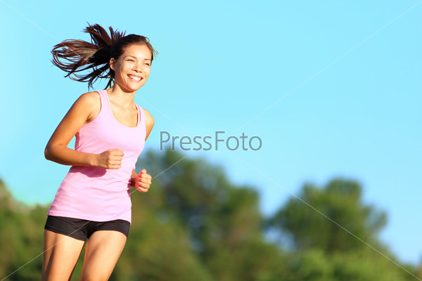Happy woman running in city park. Asian girl runner jogging smiling aspirational outside on beautiful summer day. Mixed race Asian Chinese / Caucasian female fitness sport model training outdoors.