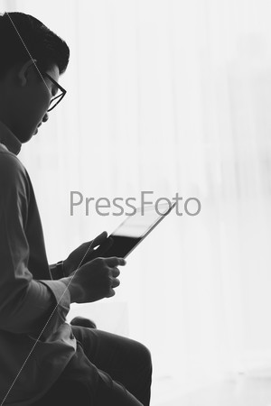 Black and white image of young man using tablet computer