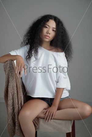 Studio portrait of sensual young woman sitting on chair