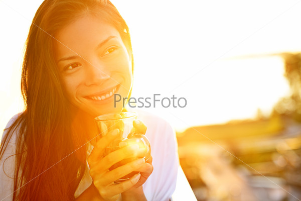 Woman Drinking Coffee In Sunshine Sitting Outdoor In Sun Light Enjoying Her Morning Coffee. Smiling Happy Multiracial Female Asian Chinese / Caucasian Model In Her 20s.