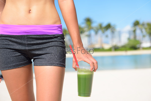 Green vegetable smoothie. Woman living healthy lifestyle drinking vegetable smoothies after fitness running workout on summer day. Beautiful fit sports model eating healthy.