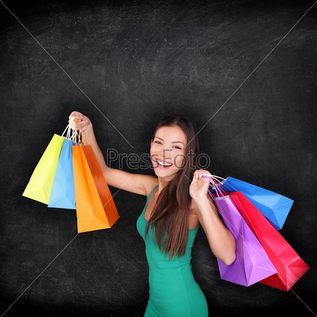 Shopping woman holding shopping bags on blackboard background with copy space for your text or design. Happy excited female shopper showing purchases excited and joyful. Mixed race Asian girl