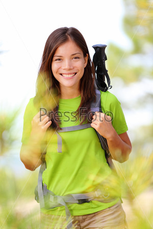 Hiker portrait - hiking woman standing smiling happy in forest clearing. Beautiful sporty healthy lifestyle image of young fresh multiracial hiker woman on trek.