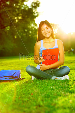 Student studying in park going back to school at university college. Happy asian girl student sitting studying, writing and reading outside. Multi ethnic Chinese Asian / Caucasian female student woman
