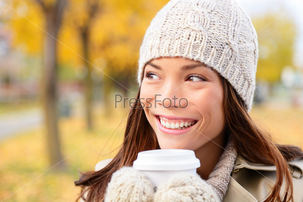 Autumn / fall woman drinking coffee looking at forest foliage copy space thinking. Happy smiling multi-ethnic Asian Chinese / Caucasian female model in red coat enjoying hot drink outdoor.