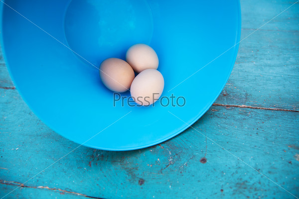 Easter - natural white eggs in a plastic bowl on an old blue vintage planked wood table. Rural or rustic kitchen still life