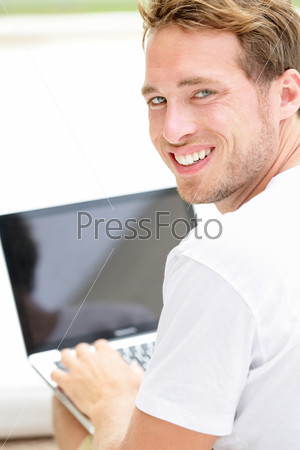 Laptop man smiling happy using computer pc outside. Young white joyful caucasian model lifestyle image.