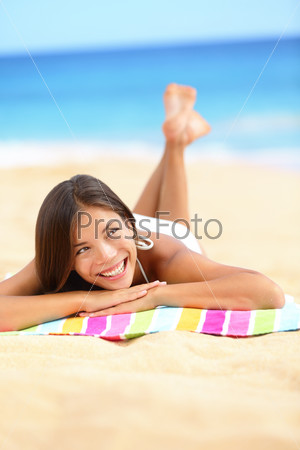 Vacation beach woman lying down relaxing and looking to the\
side and up. Happy smiling girl in bikini lying on sand on beach\
towel during summer travel holidays.