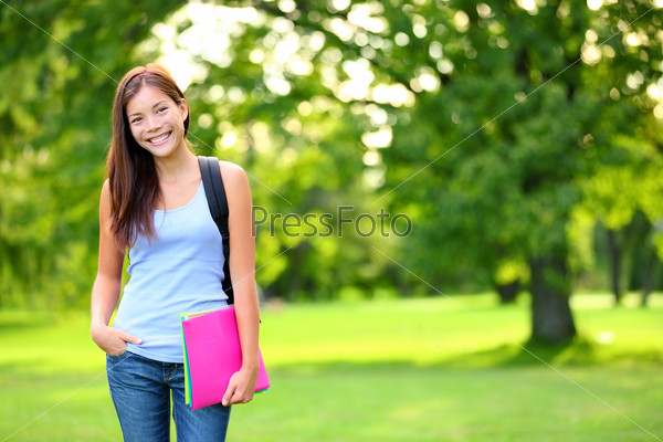 Student girl portrait holding books wearing backpack outdoor in park smiling happy going back to school. Asian female college or university student. Mixed race Asian / Caucasian young woman model.