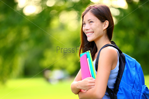 University / college student girl looking happy smiling with\
book or notebook in campus park. Beautiful young mixed race Asian\
Chinese / Caucasian young woman female model.