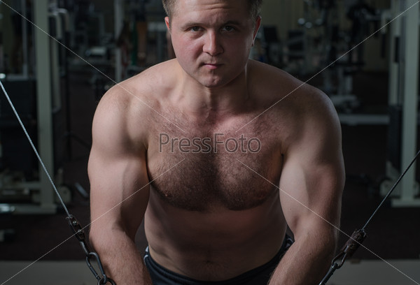 Young man at the gym exercise on the pectoral muscles, the reduction in the hands of crossover