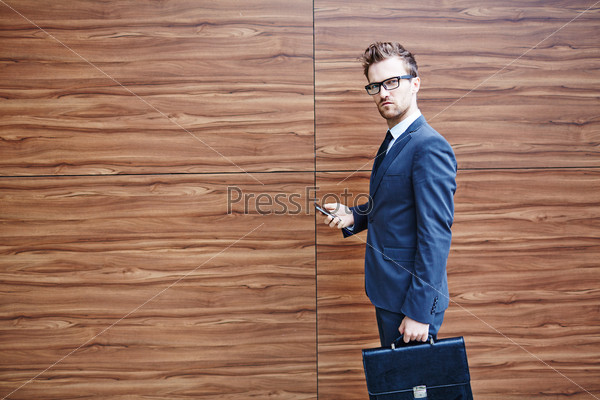 Businessman with briefcase and cellphone looking at camera