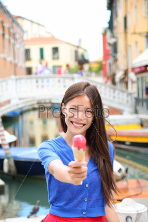 Ice cream eating woman in Venice, Italy on vacation travel showing gelato ice cream cone smiling happy looking at camera. Tourist having fun eating italian food on holidays in Venice, Italy, Europe.