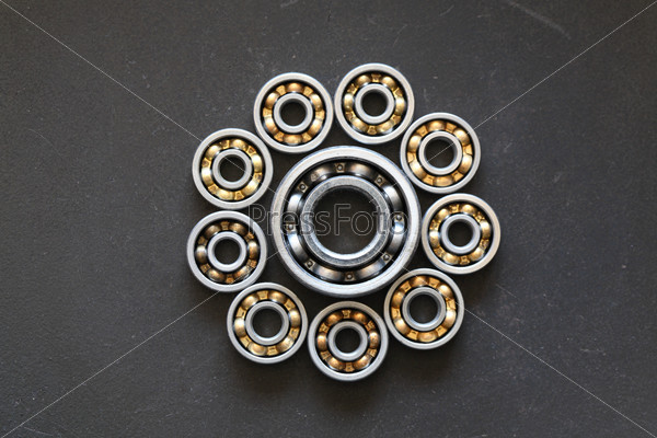 Industrial concept. Few ball bearings as circle on dark metal background