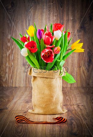 Mix tulips in the sack on wooden background