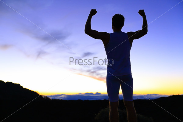Strength - strong success fitness man flexing muscles showing power pose outside in silhouette at night. Muscular fit male fitness man celebrating success macho style.