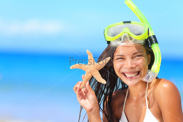 Beach travel people - woman with snorkel and starfish in bikini enjoying summer vacation holidays on tropical resort by ocean sea. Beautiful young mixed race Asian Caucasian woman smiling happy.