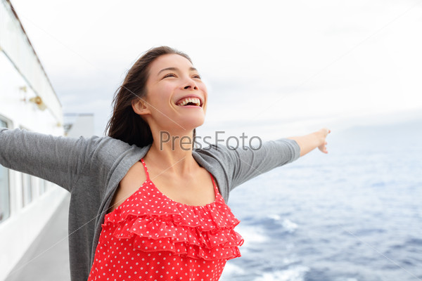Cruise ship woman on boat in happy free pose smiling enjoying freedom. Young woman traveling on vacation travel sailing on open sea ocean. Young mixed race Asian Caucasian woman.