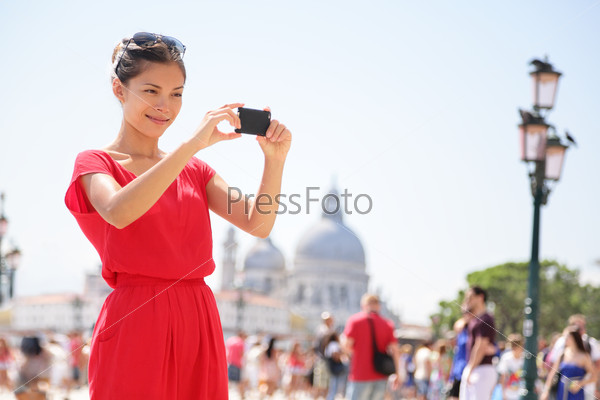 Asian woman taking picture photo with smartphone in Venice, Italy. Tourist girl using smart phone camera to take photograph on travel in Europe.