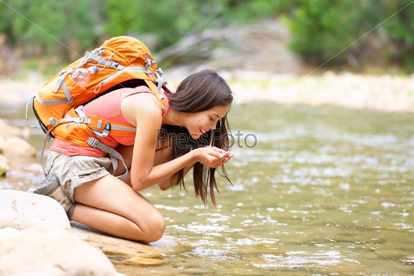 Hiker woman drinking water from river creek hiking