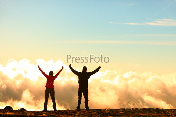 Success, achievement and accomplishment concept with hiking people cheering and celebrating of joy with arms raised outstretched up in the sky on trekking hike outside. Hikers having fun at sunset.