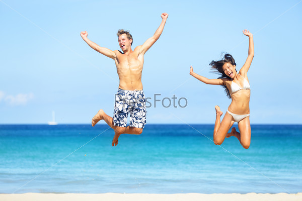 Beach people - happy couple jumping in swimwear and bikini. Sunny summer travel image with young multiracial couple on Hawaii, Big Island. Caucasian man, Asian woman