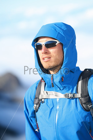 Hiking man - hiker portrait of young male hiker and climber in alpine wear hard shell jacket in high altitude mountain above the clouds.