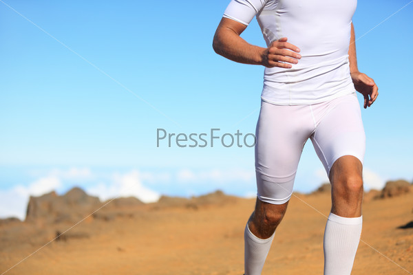 Sport fitness runner running outside in nature. Man training trail running for marathon run. Unrecognizable fit male athlete working out.