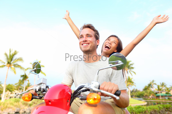 Happy free freedom couple driving scooter excited on summer\
holidays vacation Young multiethnic couple, Asian woman, Caucasian\
man