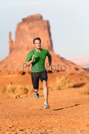 Trail running man. Male runner in Monument Valley sprinting fast training for success. Fit sports fitness model working out in amazing landscape nature. Arizona, Utah, USA.
