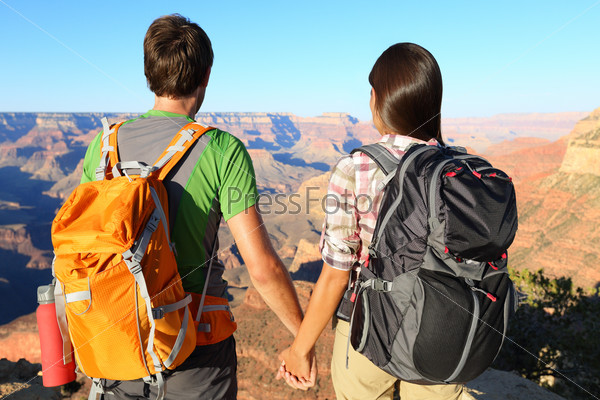 Couple holding hands looking at Grand Canyon. Romantic hikers enjoying view and romance while hiking Grand Canyon, USA.