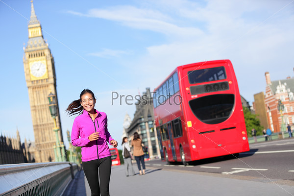 London lifestyle woman running near Big Ben. Female runner jogging training in city with red double decker bus. Fitness girl smiling happy on Westminster Bridge, London, England, United Kingdom.