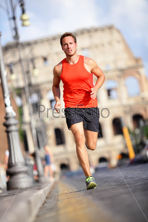 Runner - man running by Colosseum, Rome, Italy. Male athlete training for marathon jogging in city of Rome in front of Coliseum in full body length. Fit male sport fitness model jogger in run outside.