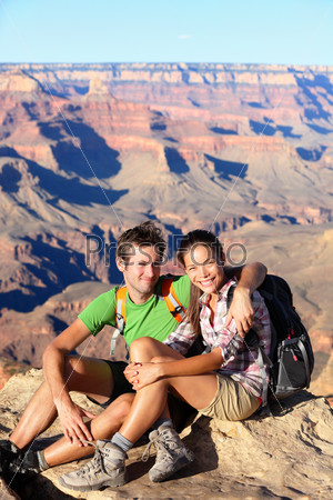 Hikers in Grand Canyon - Hiking couple portrait. Hiker man and woman enjoying view of nature landscape looking at camera smiling happy. Young couple relaxing after hike in Grand Canyon, Arizona, USA