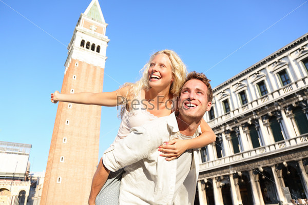 Romantic couple in love having fun embracing and laughing doing piggyback ride in Venice, Italy on Piazza, San Marco. Happy young couple on travel vacation on St Mark\'s Square. Happy woman and man.