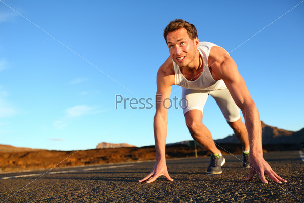 Sprinter starting sprint - man running getting ready to start sprinting run. Fit male runner athlete training outside on road in beautiful mountain landscape nature.