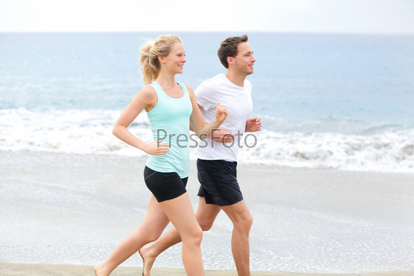 Running couple. Runners jogging on beach training together. Man and woman joggers exercising outdoors.