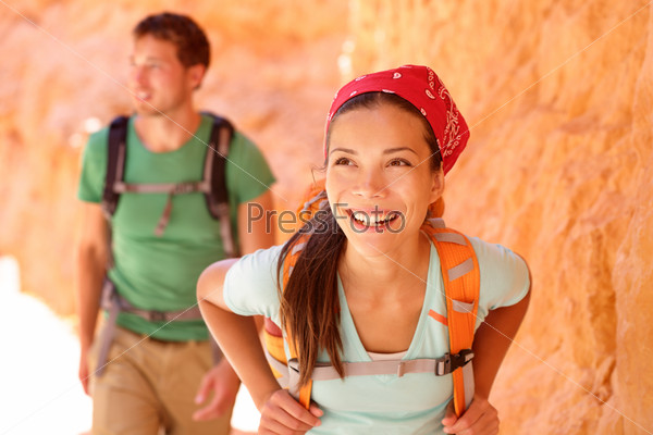 Hiking people - couple hikers in Bryce Canyon walking smiling happy together. Multiracial couple, young Asian woman and Caucasian man in Bryce Canyon National Park landscape, Utah, United States.