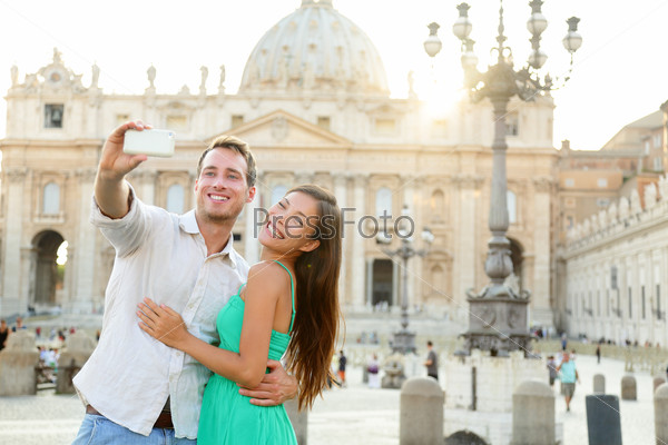 Tourists couple by Vatican city and St. Peter\'s Basilica church in Rome. Happy travel woman and man taking selfie photo picture on romantic honeymoon in Italy.