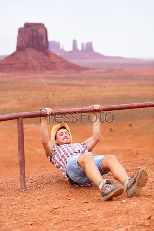 Fitness man training outdoors working out in amazing american landscape. Cowboy man doing crossfit outside in nature wearing cowboy hat and casual clothing during workout. Funny sport fitness concept.