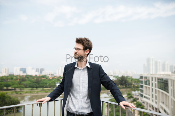 Portrait of a young businessman standing on balcony