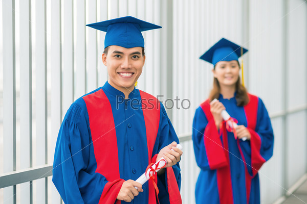 Cheerful graduates posing outdoors in gowns and hats