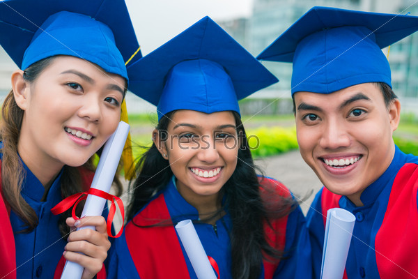 Portrait of three graduates smiling and looking at camera