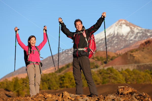 Success winning celebrating hiking people at top. Cheering hiker couple enjoying freedom on hike with arms raised in mountain landscape. Woman and man on volcano Teide, Tenerife, Canary Islands, Spain