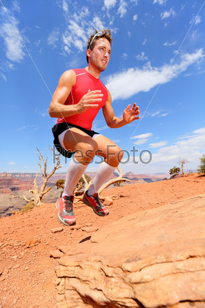 Fitness athlete bench jump squat jumping in nature landscape. Strength training fit male working out exercising outdoors in summer doing jumping on rock.