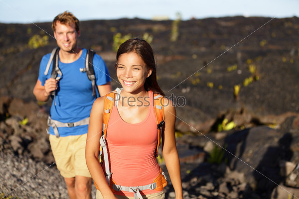 Hiking people - couple walking on lava field on Hawaii. Tourists hikers on hike near Kilauea volcano around Hawaii volcanoes national park, USA.